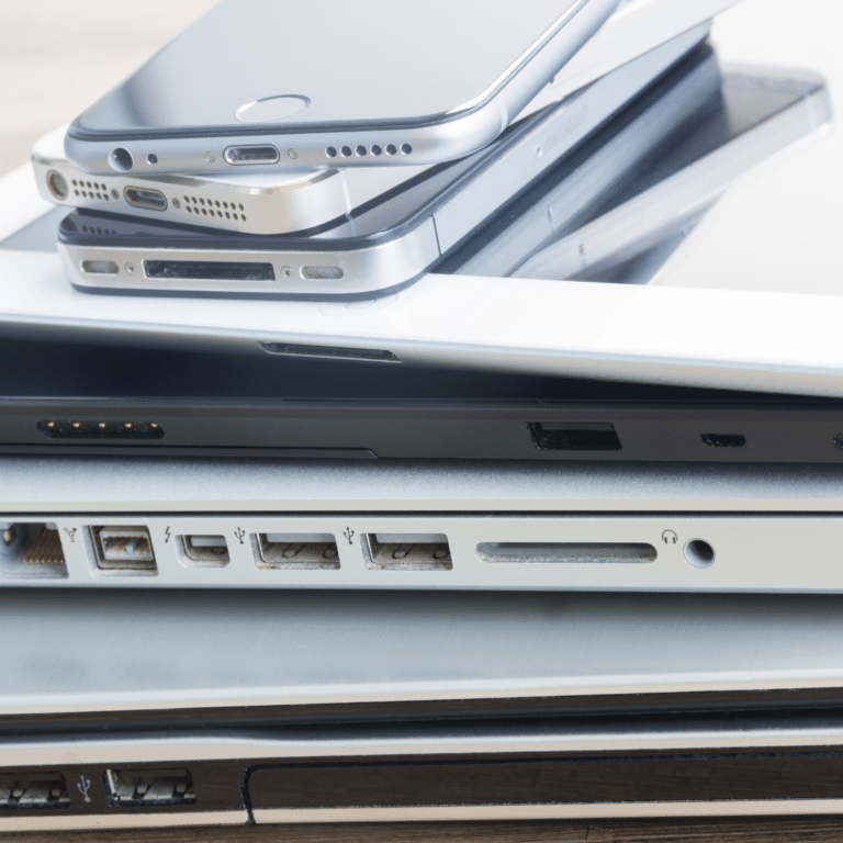 Stack of various mobile devices and laptops showcasing different charging ports and connectors, highlighting the importance of responsive design in HTML email development for compatibility across devices.